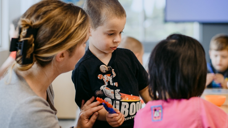 An educator and two children engaged in a classroom activity