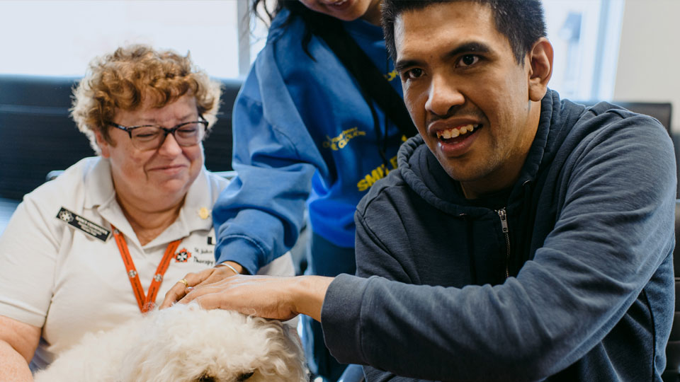 two people petting a dog with a volunteer from St. John's Ambulance