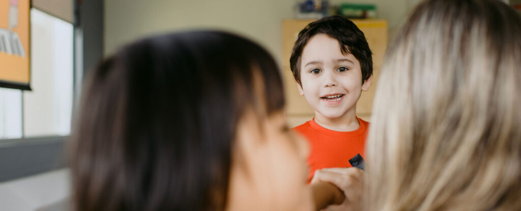 a boy in a classroom looking at the camera and smiling