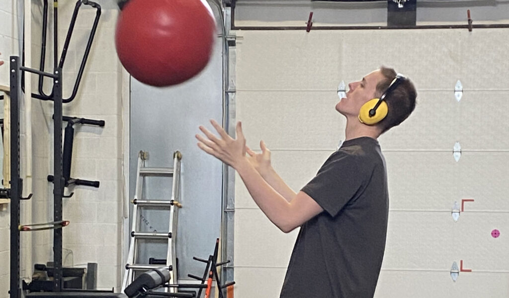 A person throwing a large red ball against a wall